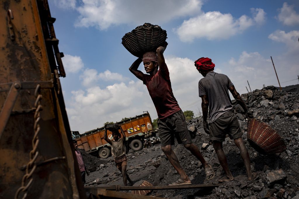 Buruh mengangkut batubara ke truk di dekat Dhanbad, India, akhir September 2021. 