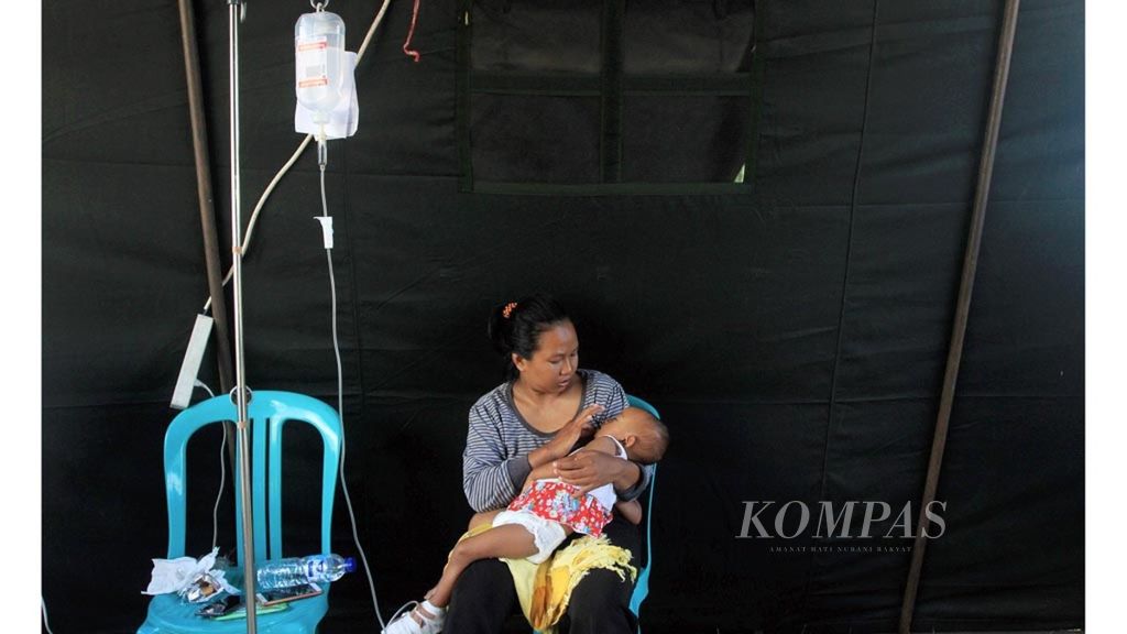 Bayi perempuan berusia 16 bulan, Baiq Adiba Shaqeena, tergolek lemas dalam pelukan sang ibu, SIti Aisyah, akibat terjangkit diare, di dalam tenda kesehatan Puskesmas Pemenang, Kabupaten Lombok Utara, Nusa Tenggara Barat, Minggu (26/8/2018).