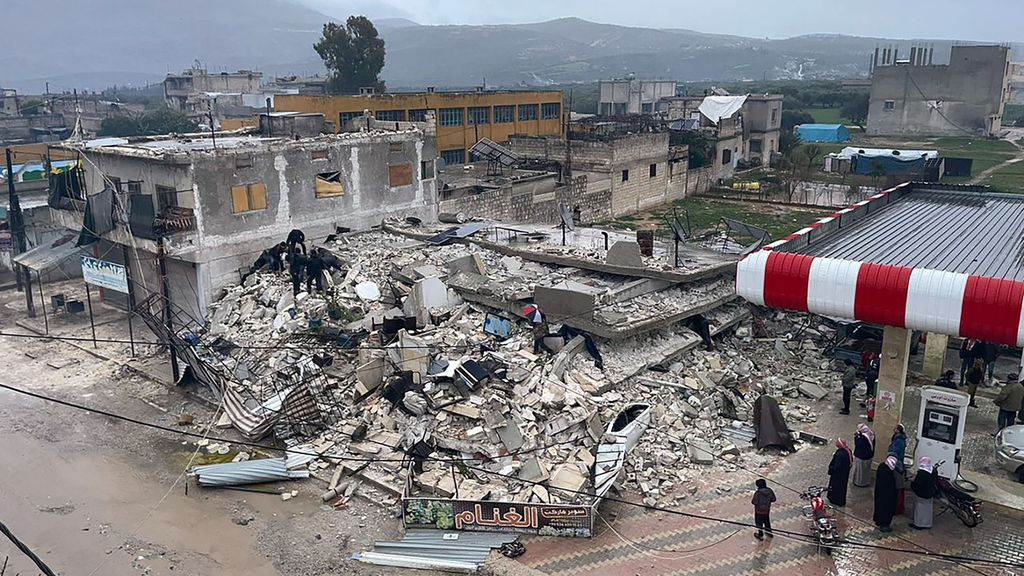 Orang-orang mencari korban di tengah puing-puing bangunan yang roboh akibat gempa di Kota Azmarin, Provinsi Idlib, Suriah. Banyak bangunan yang roboh akibat gempa ini.