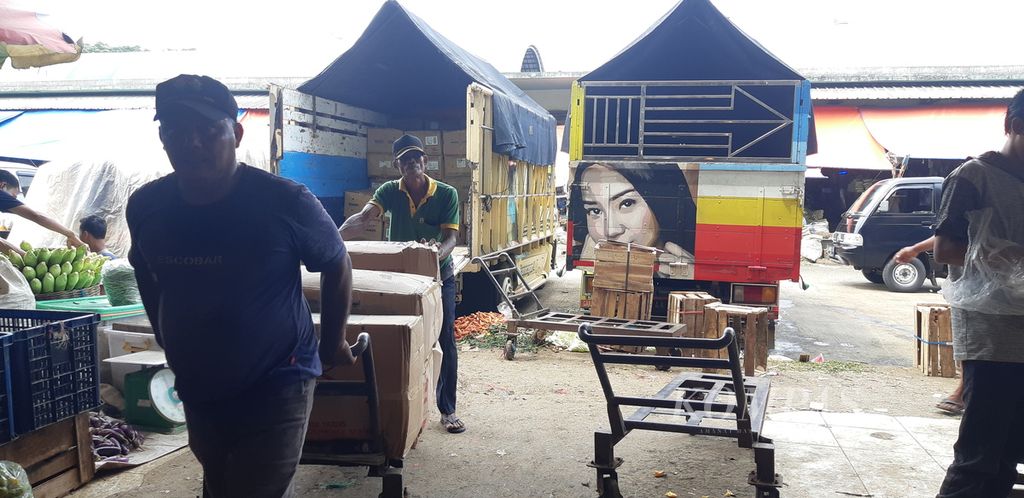Pekerja pasar tengah mengangkut bahan pokok yang baru diantar dengan truk barang untuk pedagang di Pasar Induk Kramat Jati, Jakarta Timur, Senin (9/5/2022).