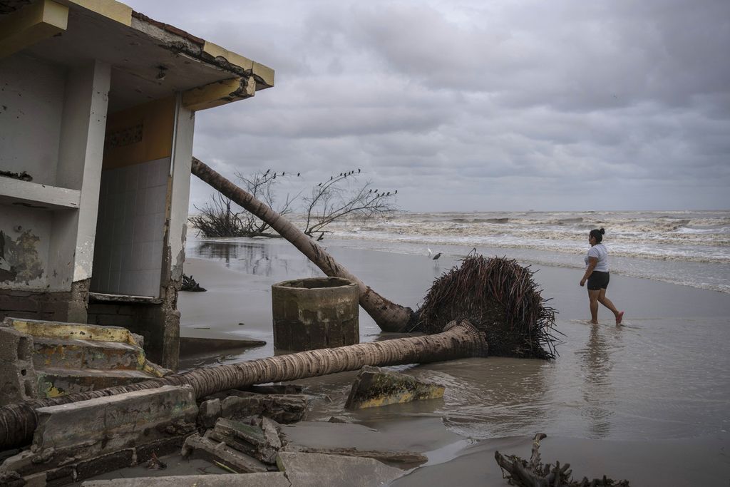 Guadalupe Cobos berjalan di sepanjang garis pantai dekat sebuah bangunan yang rusak akibat terempas ombak laut Teluk Meksiko di komunitas pesisir El Bosque, di Negara Bagian Tabasco, Rabu (29/10/2023). 