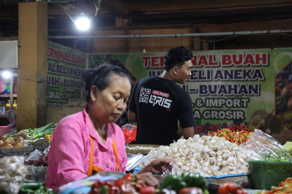 Pedagang sayuran menggunakan kaus dengan tulisan ajakan menggunakan QRIS (Quick Response Code Indonesian Standard) di Pasar Beringharjo, Yogyakarta, Rabu (14/12/2022). Kampanye transaksi nontunai dengan salah satunya menggunakan QRIS terus dilakukan di kalangan masyarakat. Namun, penelitian menunjukkan transaksi nontunai membuat orang lebih boros. 