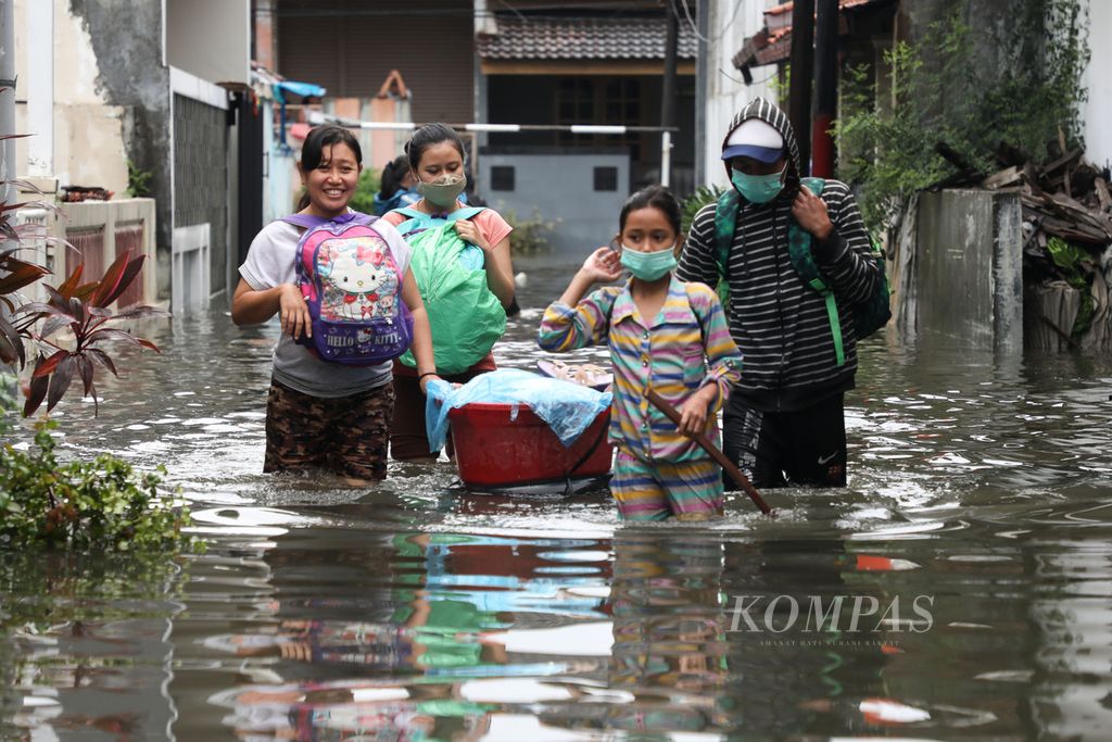 Warga melewati banjir di Panggung Lor, Semarang, Jawa Tengah, saat akan mengungsi ke rumah kerabat, Minggu (7/2/2021). 