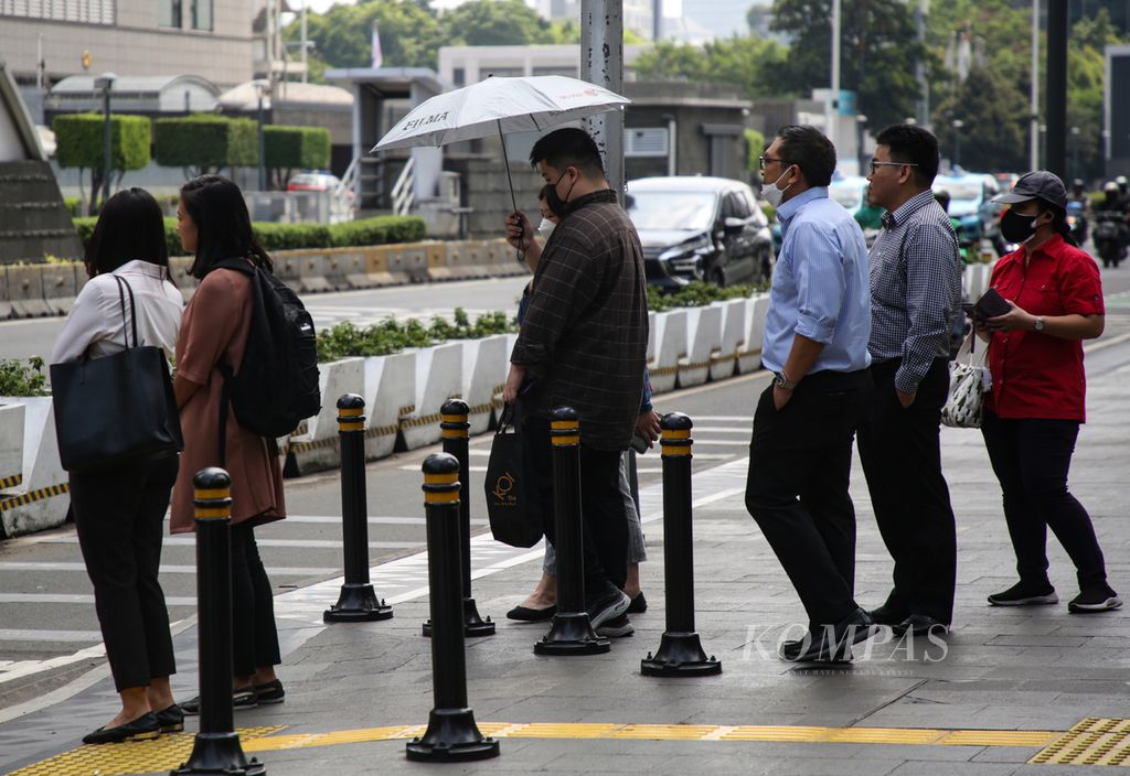 Warga menggunakan payung untuk menghindari terik matahari saat hendak menyeberang jalan protokol MH Thamrin, Jakarta Pusat, Selasa (23/5/2023). 