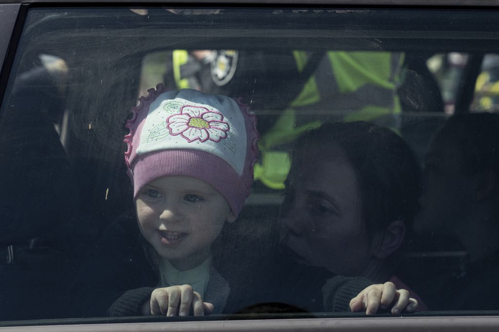 Seorang anak melihat keluar lewat jendela sebuah kendaraan yang membawa dia dan keluarganya meninggalkan Mariupol menuju pusat penampungan pengungsi di Zaporizhia, Ukraina pada Kamis (5/5/2022).