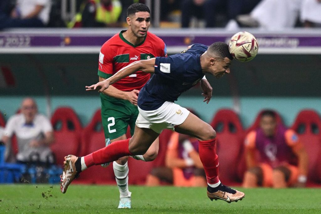 Penyerang Perancis, Kylian Mbappe (kanan), berupaya menggiring bola dengan kepalanya saat dikawal bek sayap Maroko, Achraf Hakimi, pada laga semifinal Piala Dunia 2022 di Stadion Al-Bayt di Al Khor, Qatar, Kamis (15/12/2022) dini hari WIB. Laga itu dimenangi Perancis, 2-0.