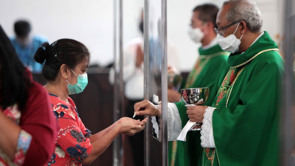 Uskup Agung Bogor Mgr Paskalis Bruno Syukur memberikan hosti saat komuni dari balik penyekat akrilik saat misa percobaan adaptasi baru di Gereja Katedral Santa Perawan Maria, Bogor, Minggu (12/7/2020). 