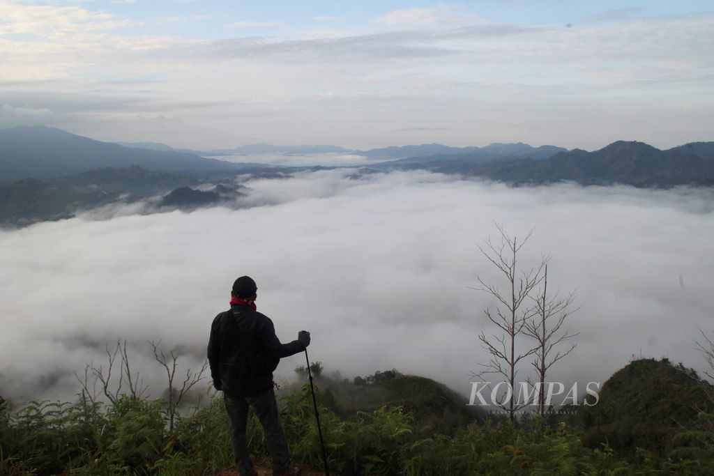 Panorama awan putih dinikmati dari Buntu Liarra, Desa Balla Tumuka, Kecamatan Balla, Kabupaten Mamasa, Sulawesi Barat, Jumat (23/3/2018). Bentangan awan memenuhi lembah di empat kecamatan. Panorama awan tersebut digemari pengunjung dalam setahun terakhir.