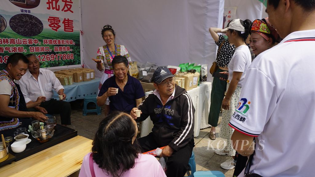 Warga lokal di kota Malipo, Distrik Wenshan, Yunnan, menikmati suguhan teh sembari bersenda gurau di salah satu tenda penjual di ajang perdana Laoshan International Tea Festival, Minggu (23/4/2023). Acara itu diadakan untuk memperkenalkan teh Malipo ke dunia. Perkebunan teh menjadi salah satu sektor andalan yang mengangkat warga Malipo dari garis kemiskinan.