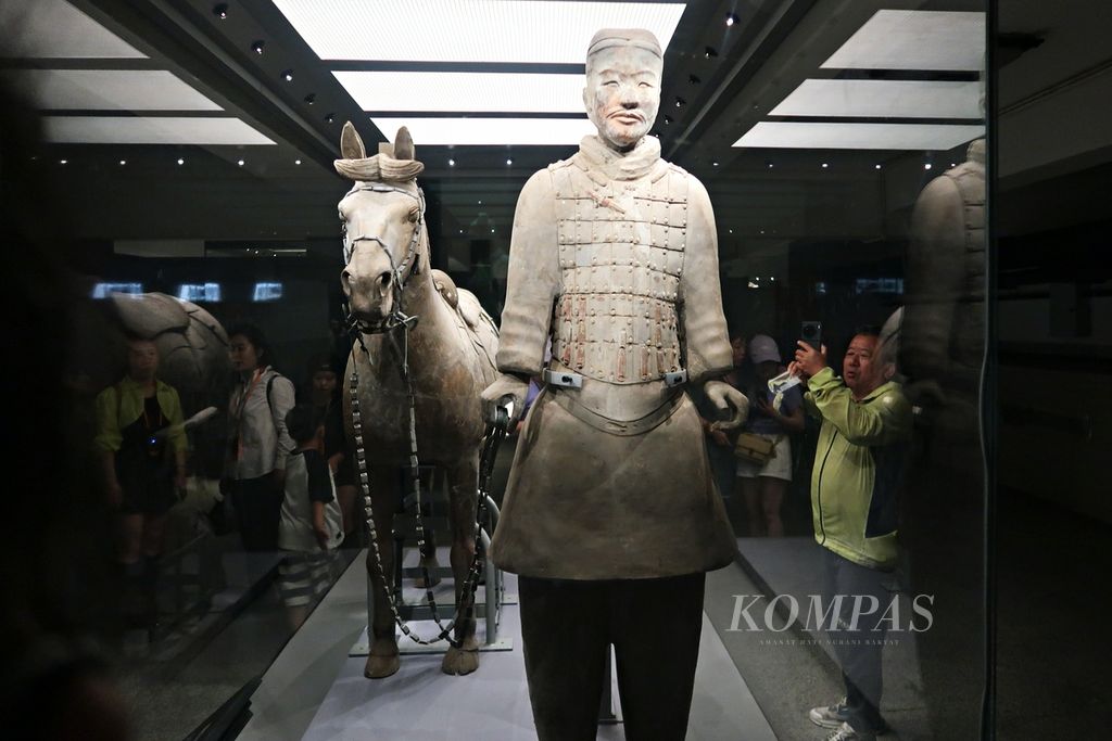 Pengunjung memotret patung anggota kavaleri terakota yang berpose bersama kudanya yang ditampilkan dalam sebuah pajangan di Museum Situs Mausoleum Kaisar Qinshihuang, Xi’an, Shaanxi, China, Rabu (17/5/2023). Sebanyak 116 patung anggota kavaleri terakota dengan kuda ditemukan di pit kedua.