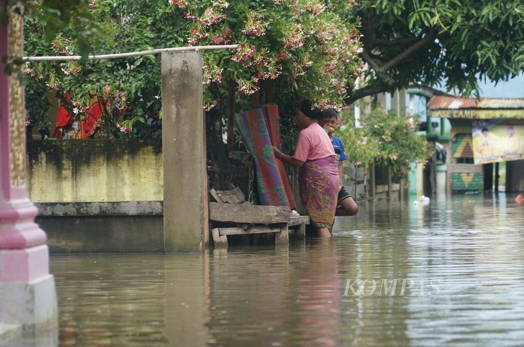 Warga sedang mengambil tikar yang ia jemur akibat basah terendam banjir akibat meluapnya Danau Kerinci di Desa Pulau Tengah, Kecamatan Keliling Danau, Kabupaten Kerinci, Jambi, Selasa (16/1/2024). 
