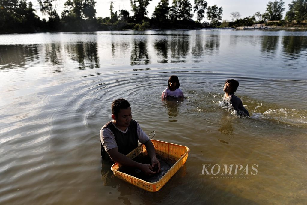  Rojani ditemani anaknya, mencuci lada putih di Danau Spritus, kolam bekas penambangan timah di kawasan Padang Baru, Bangka Tengah, Pulau Bangka, Bangka Belitung, Senin (18/7/2022).  