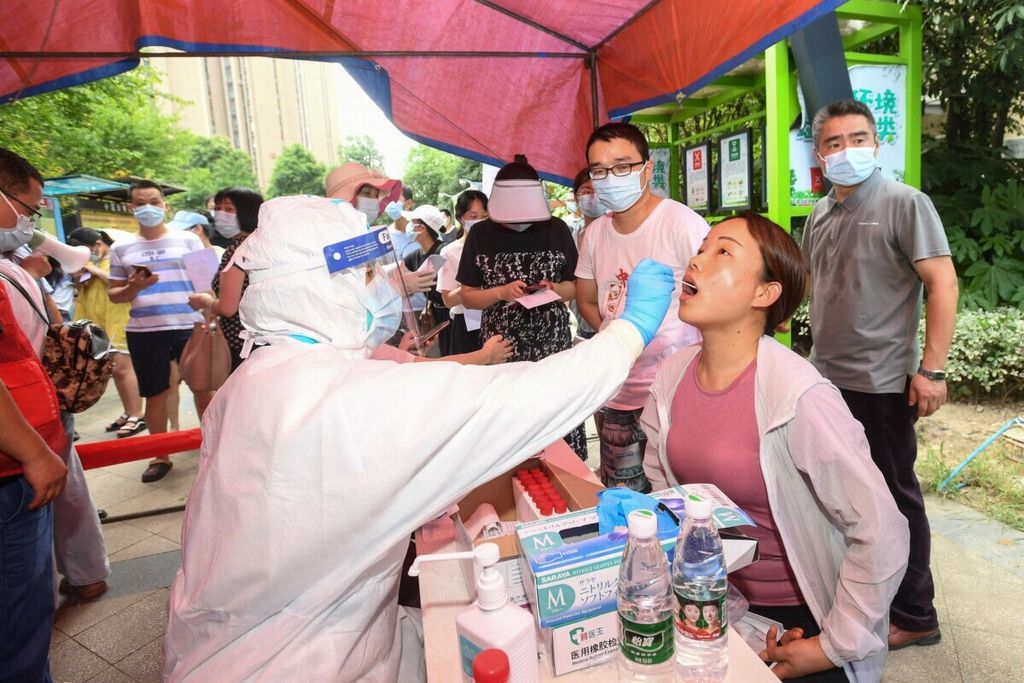 Seorang penduduk (kanan) diberikan tes asam nukleat untuk virus korona di Wuhan di Provinsi Hubei tengah China pada 3 Agustus 2021, saat kota tersebut menguji seluruh populasinya untuk Covid-19. 