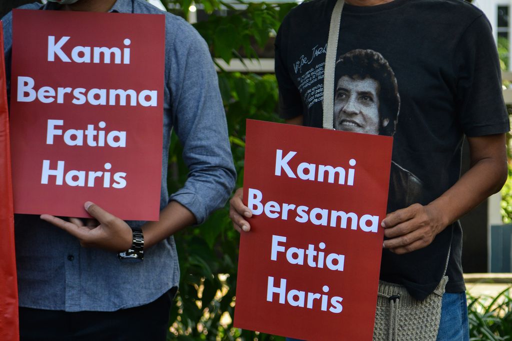 Dua peserta aksi membawa spanduk berisi dukungan kepada terdakwa dugaan pencemaran nama baik, Haris Azhar dan Fatia Maulidiyanti, di depan Pengadilan Negeri Jakarta Timur, Senin (3/4/2023). 