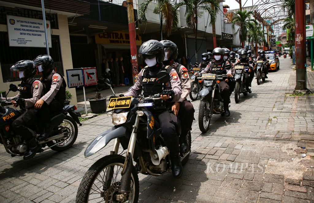Polisi mengenakan masker saat berpatroli di kawasan Pasar Baru, Jakarta Pusat, Rabu (25/3/2020).