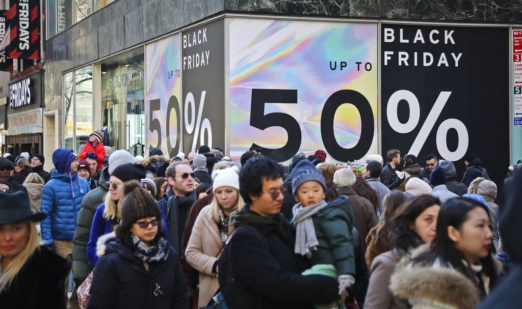 Kerumunan orang berjalan melewati papan nama toko besar yang memajang diskon Black Friday di tengah kota Manhattan, AS, pada 23 November 2018. 