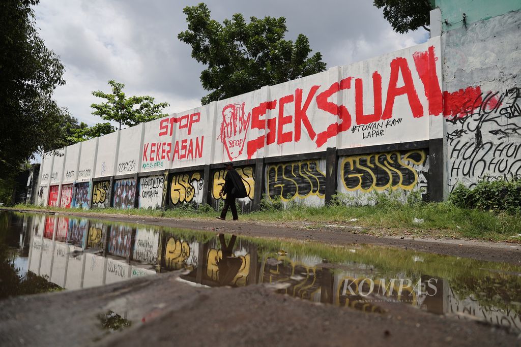 Warga melintas di depan mural di tembok Stadion Kridosono, Yogyakarta, Senin (10/1/2021). Mural itu berisi seruan untuk mendorong pengesahan Rancangan Undang-Undang Tindak Pidana Kekerasan Seksual.