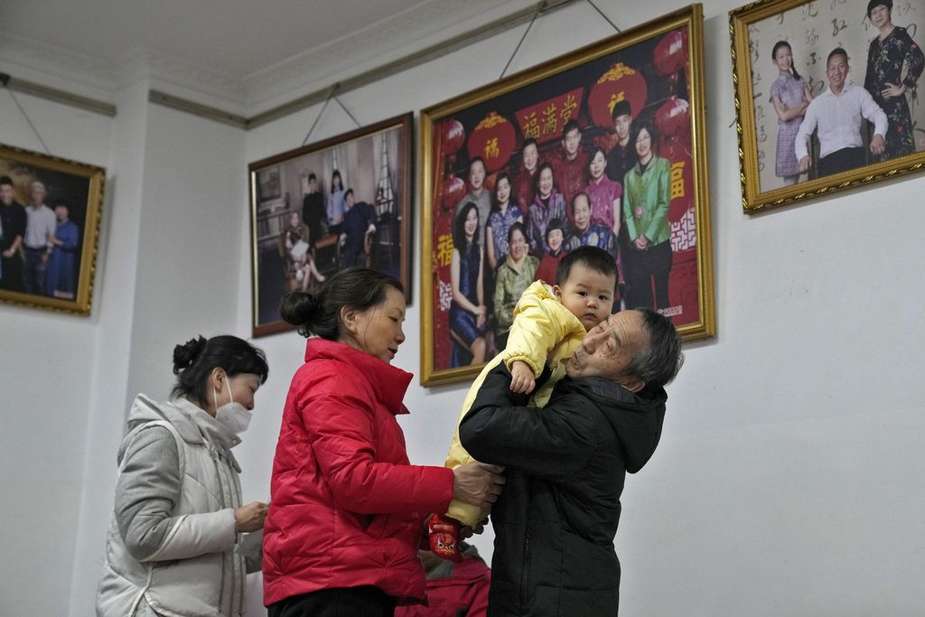 Seorang kakek menggendong cucunya bersiap untuk pergi setelah mengambil foto keluarga bersama di sebuah studio foto di Beijing, Selasa, 17 Januari 2023. 