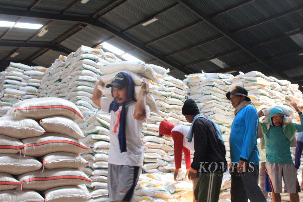 Workers are transporting sacks of rice from the warehouse to a truck at Bulog Tuk Warehouse on Brigadier General Dharsono Road, Cirebon, West Java, on Tuesday (19/9/2023).