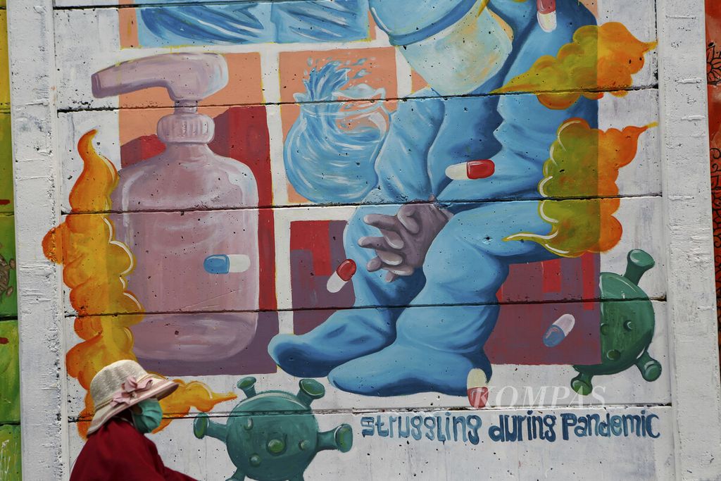 Warga melintasi mural bergambar tenaga kesehatan bertema Pejuang Masa Kini di Jatiasih, Kota Bekasi, Jawa Barat, Minggu (14/11/2021). Selain untuk mewarnai kota, dengan mural tersebut juga mengajak warga untuk terus menaati protokol kesehatan. 