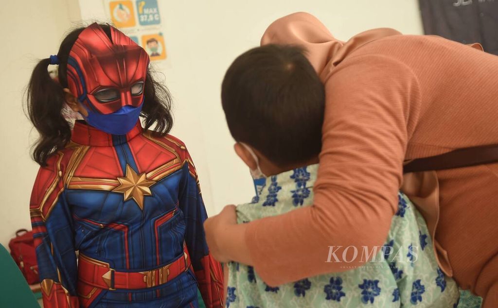 Siswa berkostum<i> superhero</i> membantu menenangkan teman mereka yang takut menjalani vaksinasi dosis kedua di SD Pembangunan Jaya 2, Kabupaten Sidoarjo, Jawa Timur, Kamis (17/2/2022).