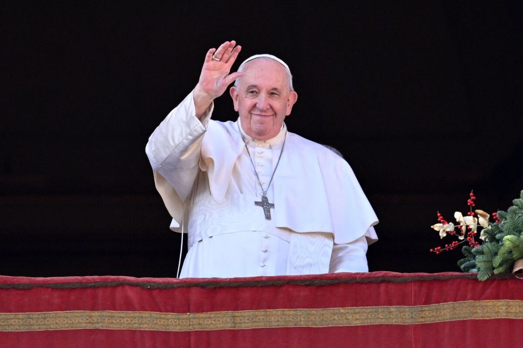 Paus Fransiskus melambai ke arah kerumunan umat saat tampil di balkon untuk memberikan berkat Natal di Santo Petrus Square, Vatican, 25 Desember 2022. 