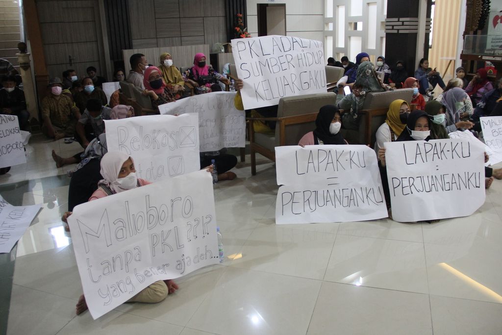 Sejumlah pedagang kaki lima (PKL) kawasan wisata Malioboro, Kota Yogyakarta, membentangkan poster di Gedung DPRD Kota Yogyakarta, Senin (17/1/2022). Dalam kesempatan itu, para PKL mendesak rencana relokasi PKL Malioboro ditunda satu hingga tiga tahun.