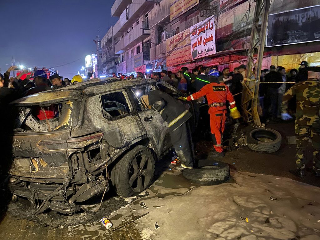 Petugas penyelamat Irak memeriksa mobil yang jadi sasaran serangan Amerika Serikat di Baghdad, Irak, pada Rabu (7/2/2024) malam. Serangan itu menyasar petinggi milisi Irak.