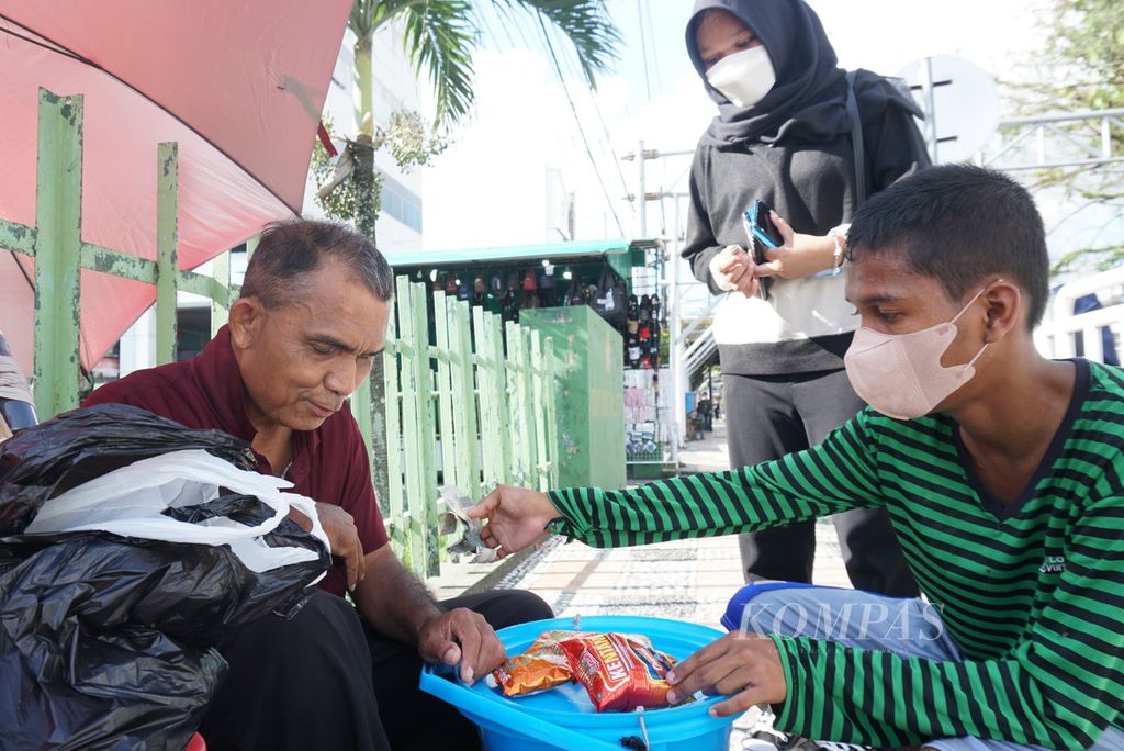 Warga membeli makanan ringan yang dijual Gurinces Muli (60, kiri), seorang difabel netra, Sabtu (16/4/2022), di bilangan Wenang Utara, Manado, Sulawesi Utara.