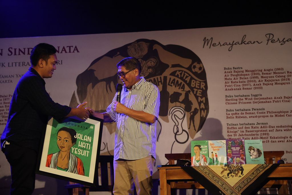 Wartawan senior Sindhunata menerima gambar sampul salah satu buku yang diluncurkan dari GM Gramedia Pustaka Utama Andi Tarigan (kiri) di Omah Petroek, Desa Hargobinangun, Pakem, Sleman, DI Yogyakarta, Minggu (15/5/2022). 