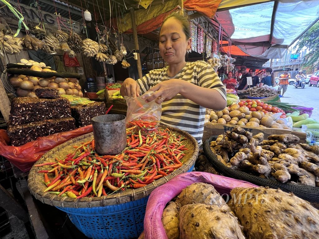 Musdalifah (38), pedagang cabai dan sayuran di Pasar Terong, Makassar, membungkus cabai untuk pembeli, Senin (30/10/2023). Saat ini harga cabai di Makassar naik tinggi.