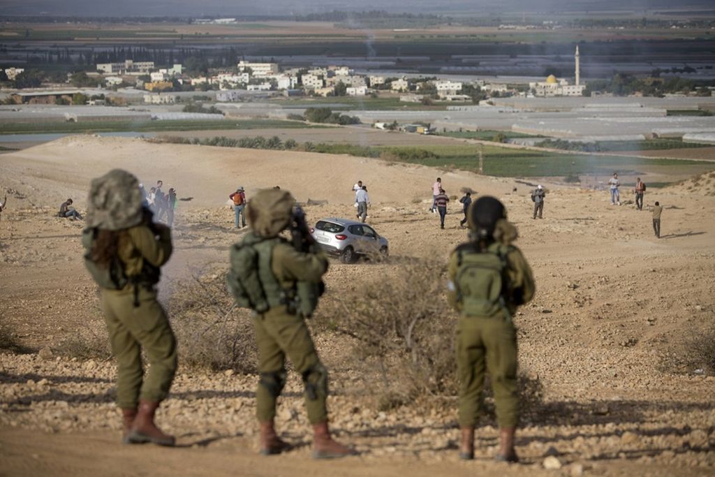 Warga Palestina dan aktivis Israel berlari menghindari gas air mata yang ditembakkan tentara Israel dalam unjuk rasa menentang pembangunan permukiman Yahudi di Lembah Jordan, Tepi Barat, 17 November 2016.