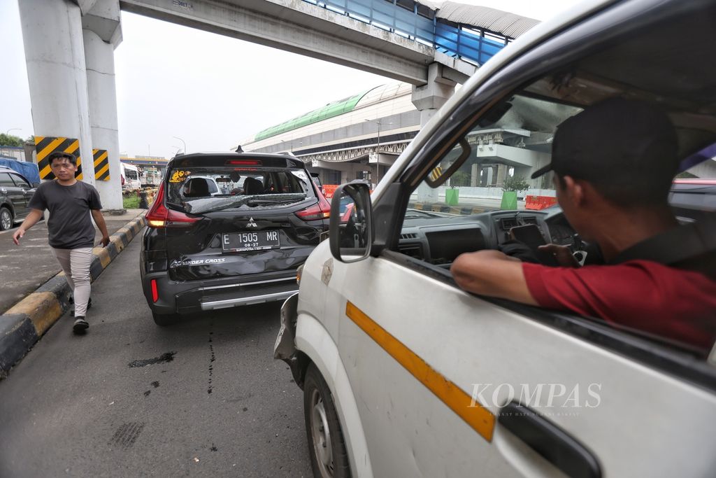 Salah seorang warga melintas di depan mobil yang mengalami kecelakaan beruntun di Gerbang Tol Halim Utama, Jakarta, Rabu (27/3/2024).