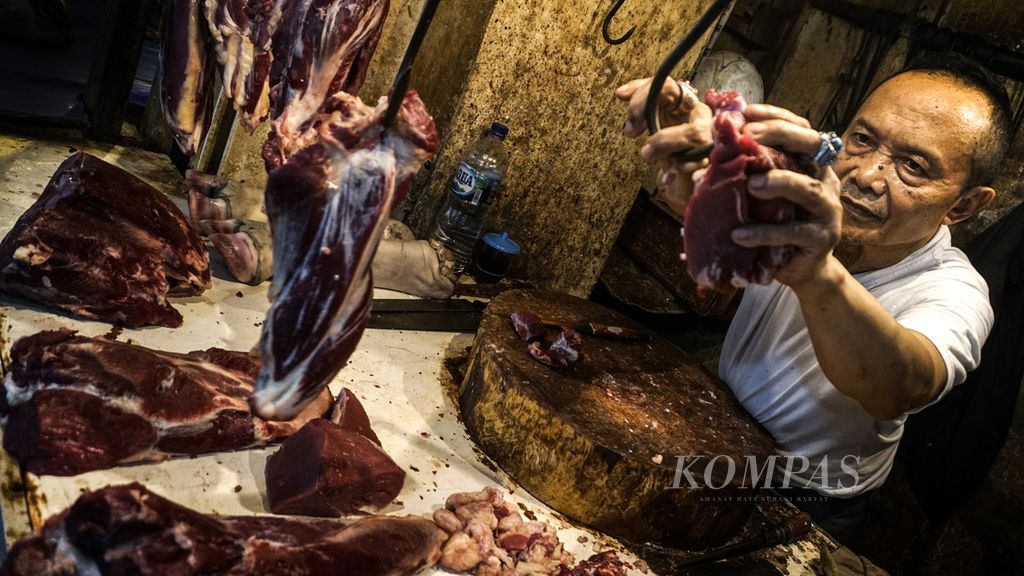 Mufid (62), pedagang daging di Pasar Bogor, Kota Bogor, Jawa Barat, menggantung sisa irisan daging di pengait yang kosong, Rabu (23/2/2022). 