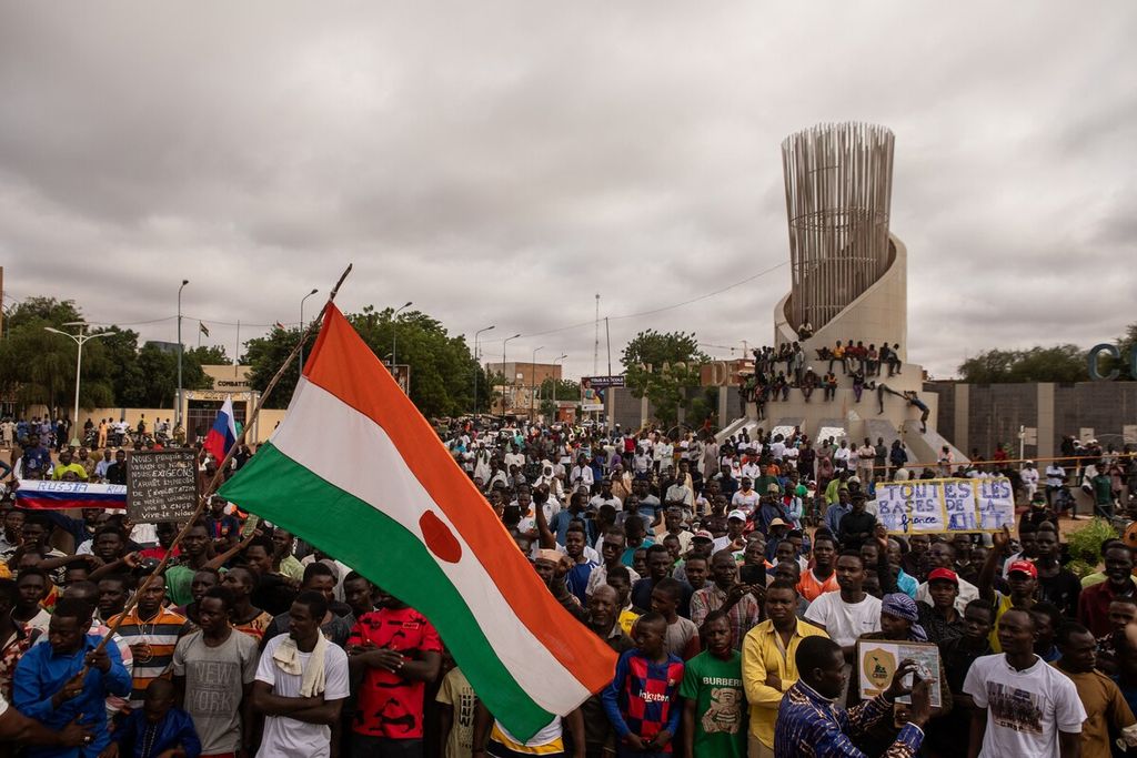 Warga memegang bendera Niger di Niamey, 3 Agustus 2023. Warga Niger pendukung junta militer melakukan makar terhadap Presiden Mohamed Bazoum melakukan arak-arakan di alun-alun kota.