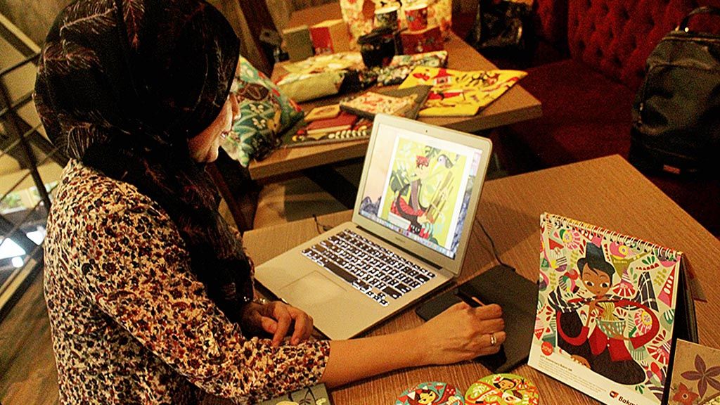 Eridanie Zulviana,  pendiri dan ilustrator Sepiring Indonesia, sedang  menyelesaikan ilustrasi. Di sampingnya terdapat kalender duduk Bakmi GM dengan ilustrasi budaya Jakarta karyanya.