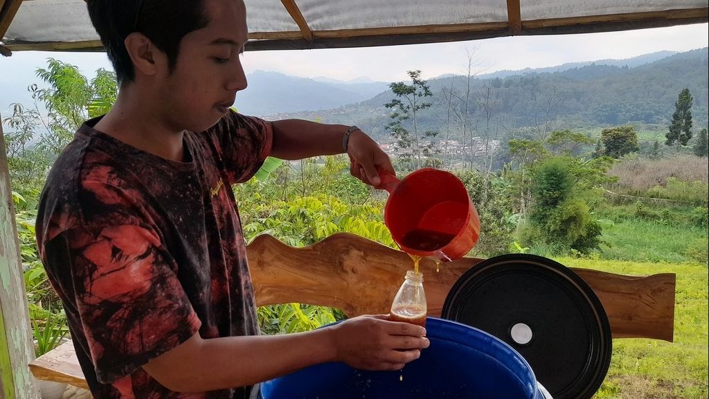 Haris Yudistiro (24) menuangkan <i>eco-enzyme</i> ke dalam botol di Dusun Gondang, Desa Tulungrejo, Kecamatan Bumiaji, Kota Batu, Jawa Timur, Senin (13/6/2022).