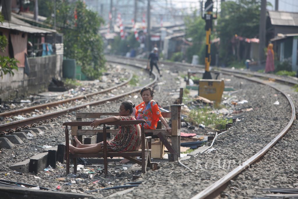 Warga berjemur di ruang terbuka yang berada di antara jalur kereta di kawasan hunian semipermanen padat penduduk di Pademangan, Jakarta Utara, Jumat (30/8/2024).