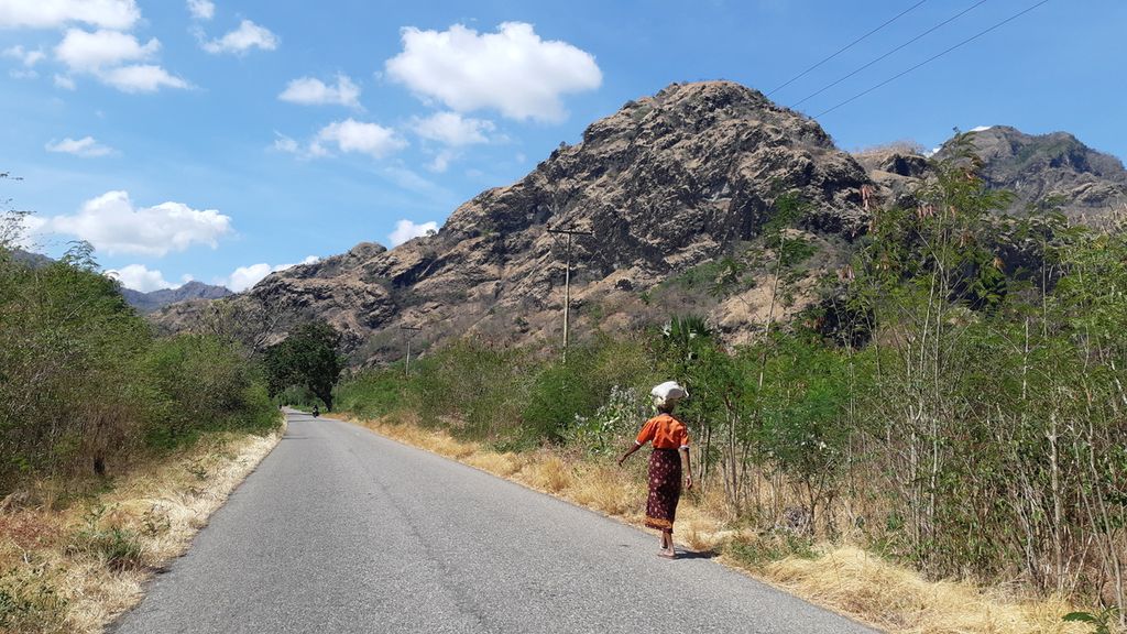 Salah satu ruas jalan penghubung antara Pos Lintas Batas Negara Terpadu (PLBNT) Wini ke PLBNT Napan di Pulau Timor, Nusa Tenggara Timur, seperti pada September 2022. Jalur itu digunakan warga Timor Leste ke dan dari Oeccuse, daerah enklave yang dikelilingi wilayah Indonesia. Oeccuse berada di balik bukit itu.