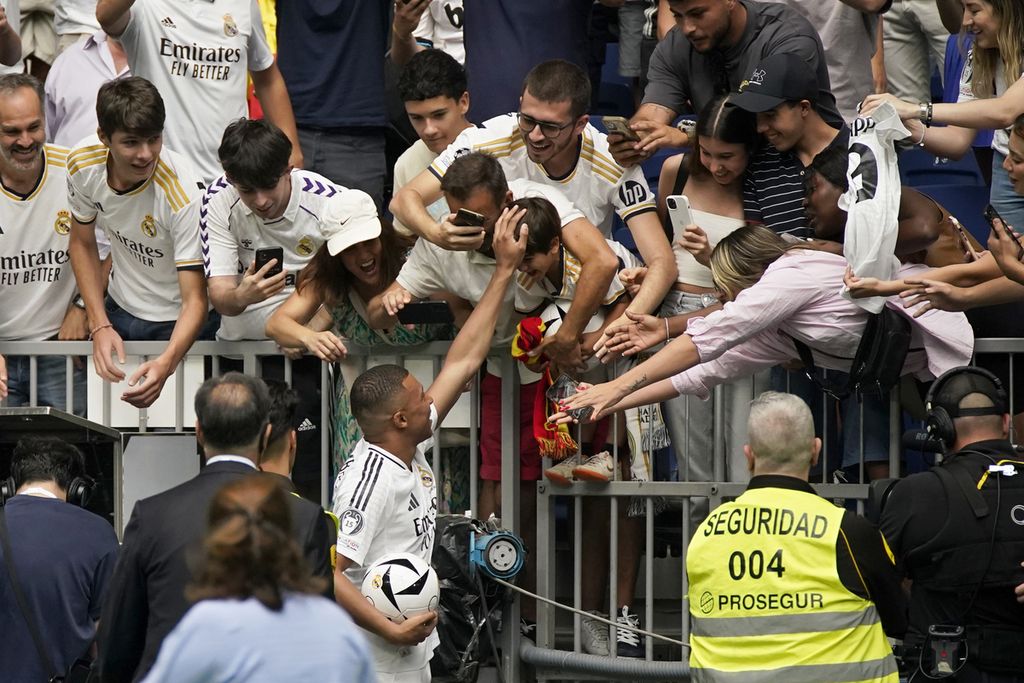 Kylian Mbappe, penyerang asal Perancis, menyambut penggemar dalam acara pengenalan sebagai pemain baru Real Madrid di Stadion Santiago Bernabeu, Madrid, Spanyol, Selasa (16/7/2024). Real bertambah kuat dengan kehadiran Mbappe.