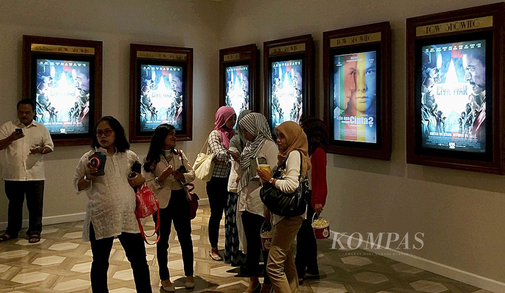 Calon penonton film menunggu diputarnya film di dekat poster film <i>Civil War</i> dan <i>Ada Apa Dengan Cinta 2</i> di sebuah bioskop di Jakarta, Kamis (28/4/2016). 