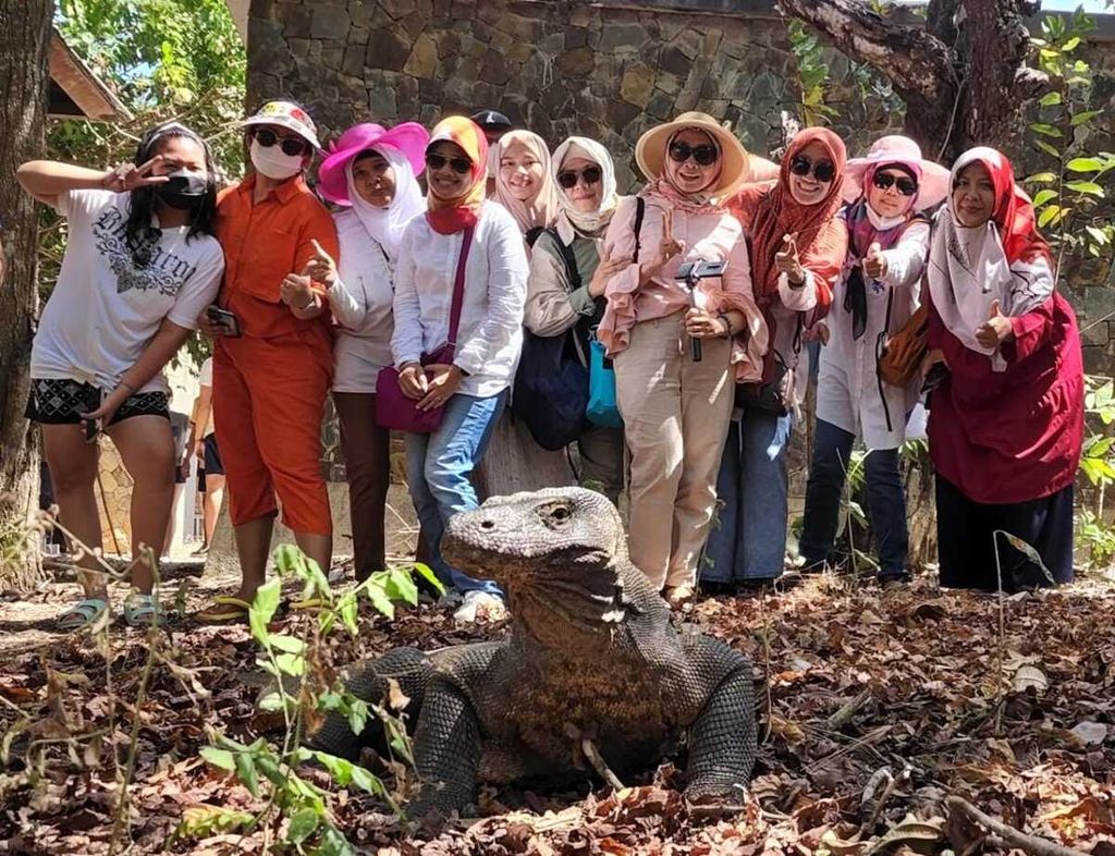 Ratna Umi (kedua dari kiri), wisatawan lokal asal Tangerang, Banten, bersama rekan-rekannya dari Jakarta dan sekitarnya foto bersama seekor komodo di Pulau Komodo, Rabu (27/7/2022). 