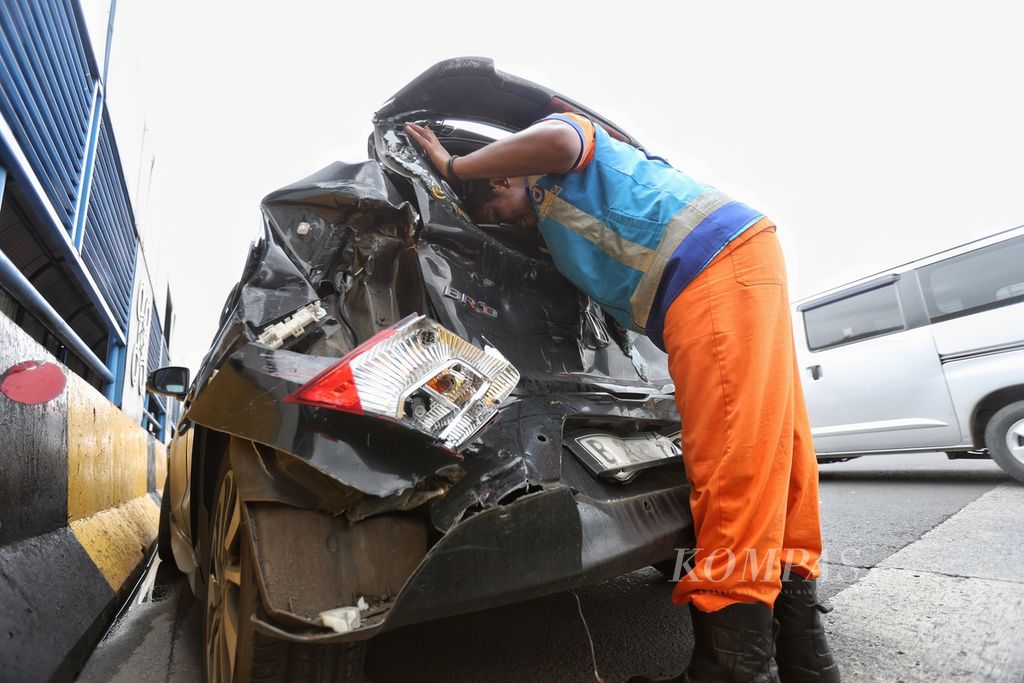 Petugas memeriksa bagian mobil yang mengalami kecelakaan di Gerbang Tol Halim Utama, Jakarta, Rabu (27/3/2024). Terjadi kecelakaan beruntun tujuh kendaraan di Gerbang Tol Halim Utama. Kecelakaan terjadi akibat sopir truk yang diduga mengendarai secara ugal-ugalan. 
