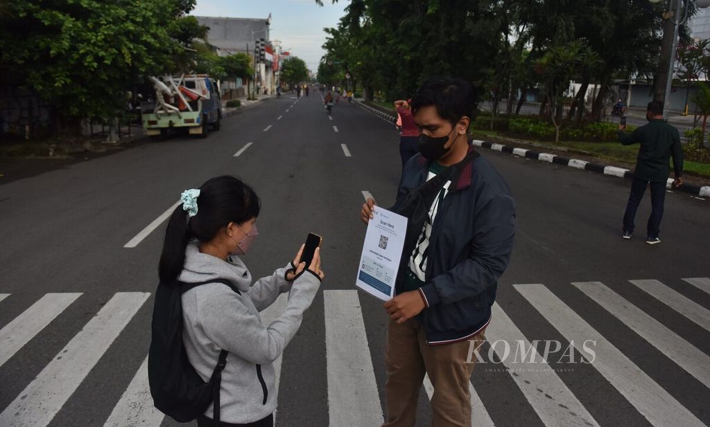 A women access the "Peduli Lindungi" application when entering the Car Free Day area on Jalan Kertajaya, Surabaya City, East Java, Sunday (20/3/2022).
