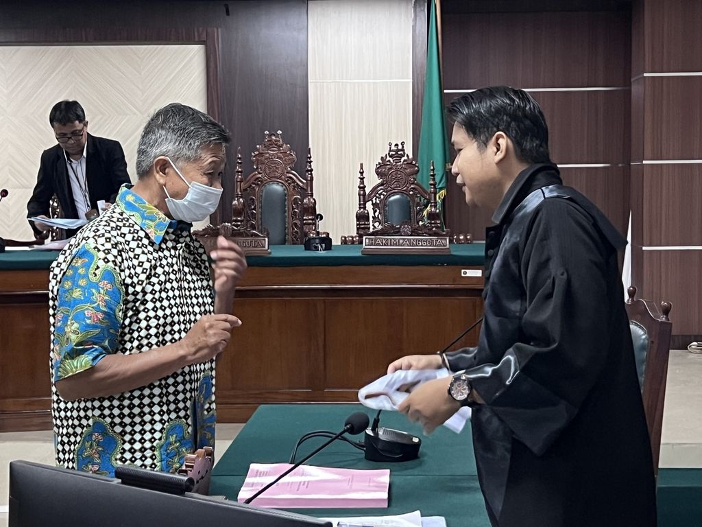 Terdakwa kasus pelanggaran HAM berat Paniai, Mayor Infanteri (Purn) Isak Sattu, berbicara dengan penasihat hukumnya di Pengadilan Negeri Makassar, Senin (14/11/2022). Jaksa menuntut Isak dengan hukuman penjara 10 tahun.