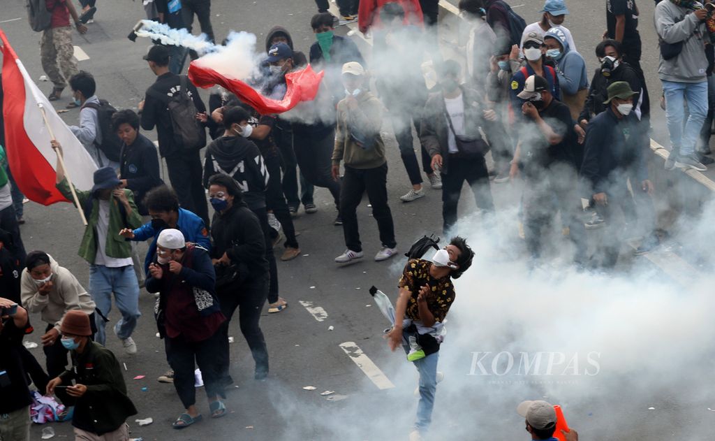 Peserta aksi melempar balik tabung gas air mata yang ditembakkan petugas kepolisian saat terjadi bentrok dalam demonstrasi mahasiswa di depan Kompleks Parlemen, Senayan, Jakarta, Senin (11/4/2022). 