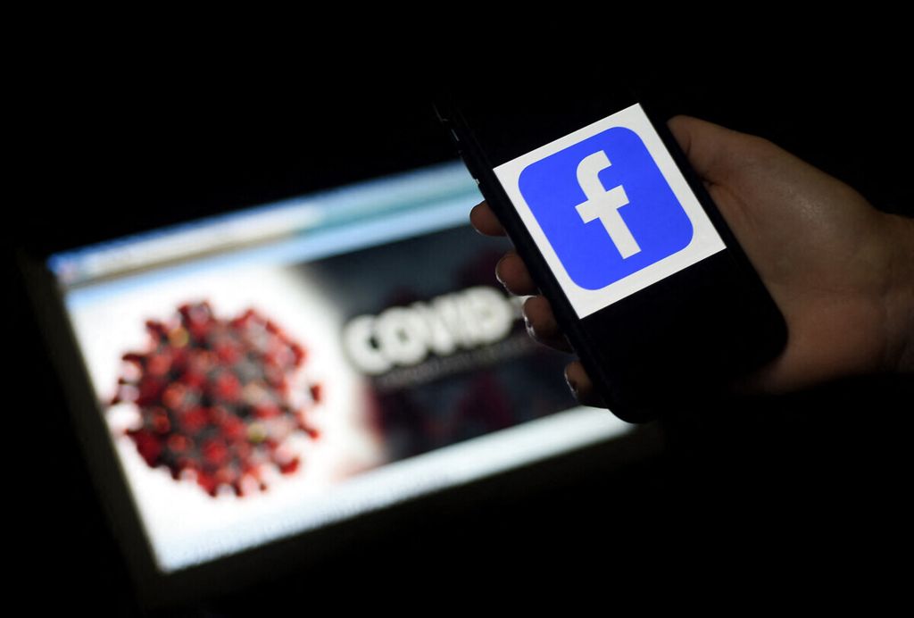Logo media sosial Facebook ditampilkan di samping ilustrasi virus Sars-Cov-2 penyebab Covid-19 pada 25 Maret 2020. Ilustrasi yang dibuat di Arlington, Negara Bagian Virginia, Amerika Serikat, ini menggambarkan Facebook menutup akun-akun yang menyebarkan hoaks terkait dengan pandemi Covid-19. 