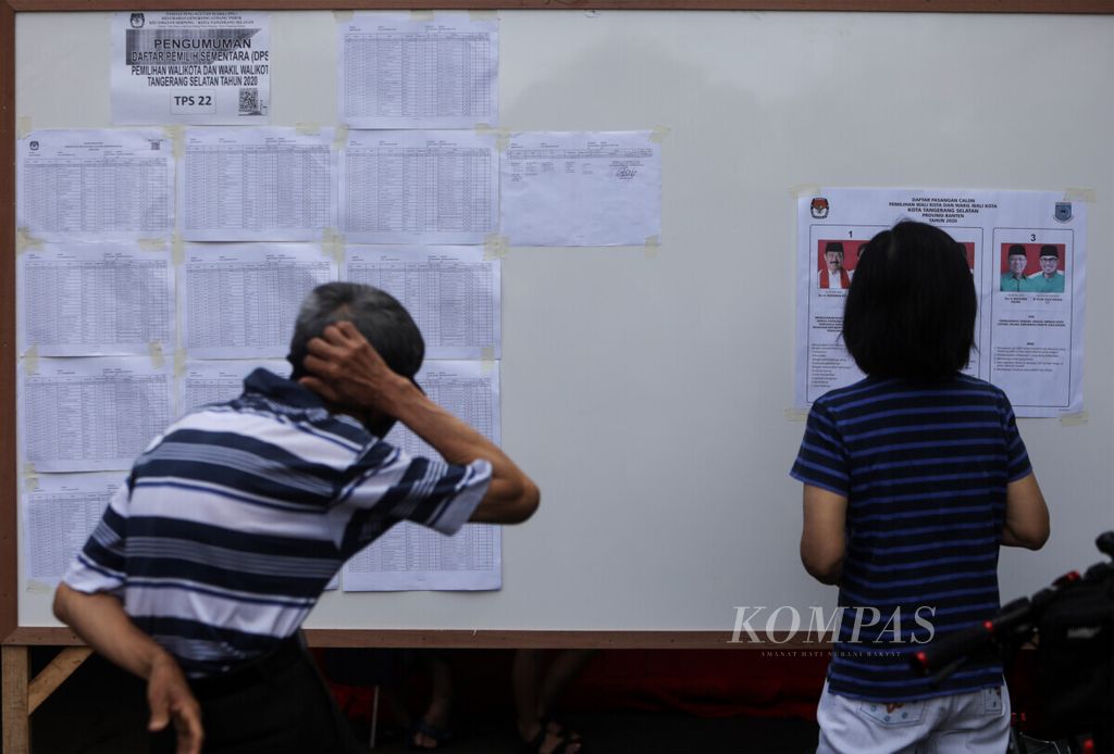 Warga melihat dan mengamati visi dan misi calon wali kota dan calon wakil wali kota sebelum memberikan suara dalam Pilkada Kota Tangerang Selatan, Banten, Rabu (9/12/2020).