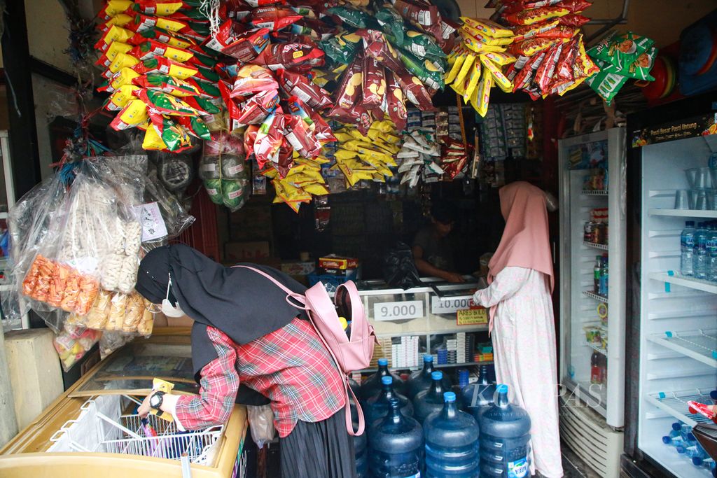 Dua perempuan berbelanja di warung klontong madura milik Wahyudi di Jalan Kertamuki, Ciputat, Tangerang Selatan, Banten, Selasa (8/11/2022). Warung klontong madura yang buka 24 jam mampu bersaing dengan minimarket yang menjamur. 