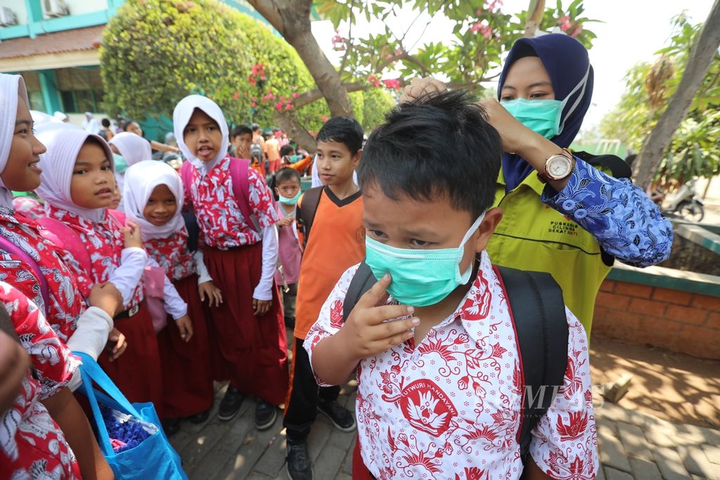 Siswa SDN 07 Pagi Cilincing menerima pembagian masker dari petugas Puskesmas Kecamatan Cilincing, Jakarta Utara, September 2019. Siswa SDN Cilincing, Jakarta Utara, terpapar polusi udara dari industri rumah tangga pembakaran arang dan peleburan timah di sekitar sekolah. 
